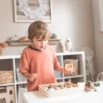 un copil fericit care se joaca cu jucarii Montessori